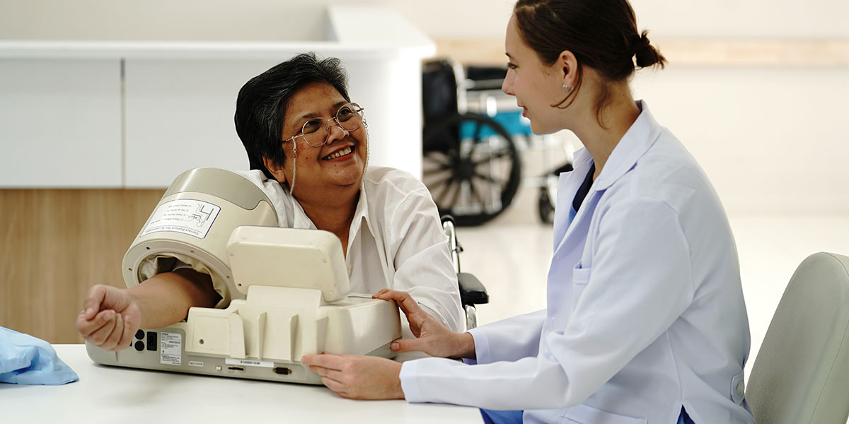 A patient getting her blood pressure measured while smiling at a doctor.