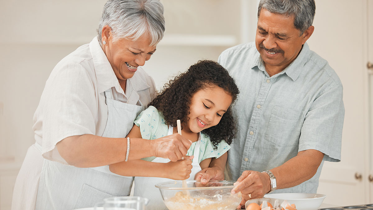 Grandparents and grandchild baking while smiling.