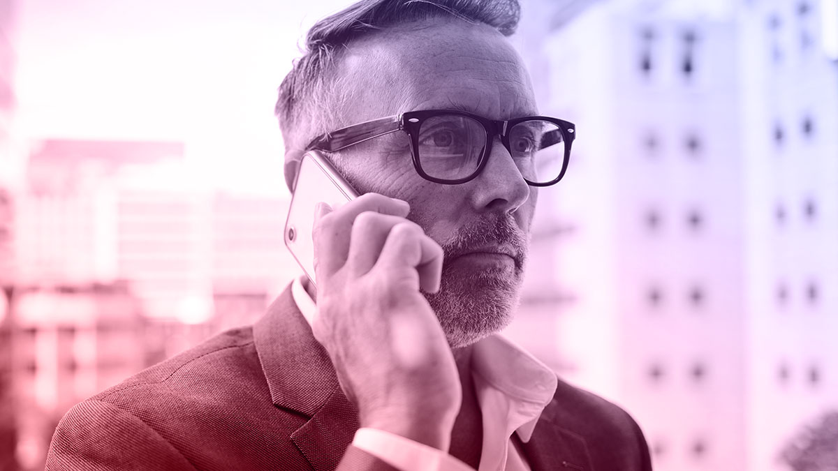 A middle aged man talking on the phone while looking pensive.