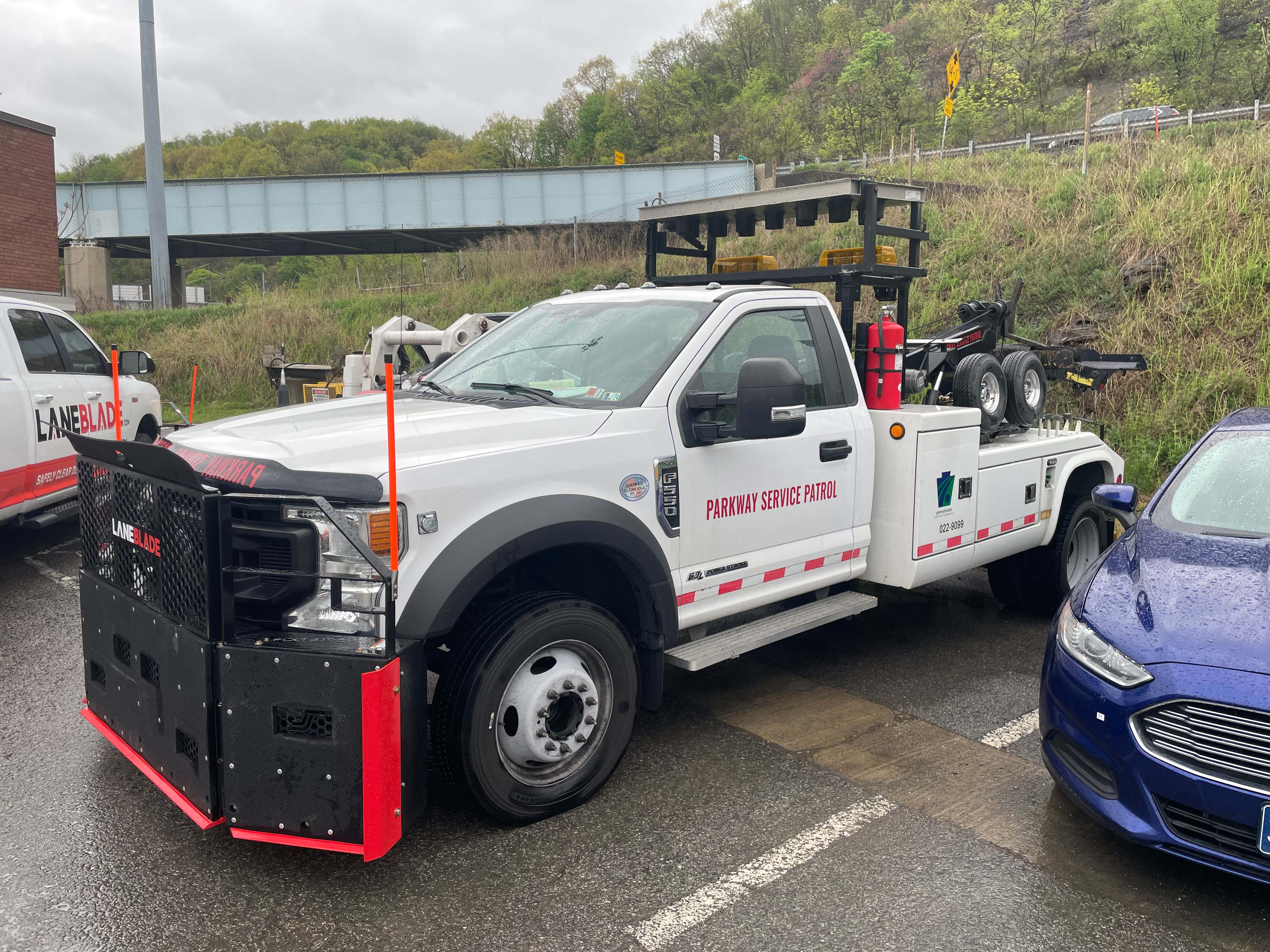 A sideview image of a PennDOT pick-up truck with a large black metal LaneBlade with red trim mounted to the front.